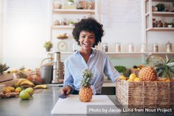 Portrait of cheerful young woman standing behind juice bar with a pineapple 5a3qPb