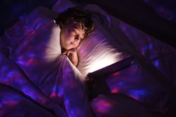 Boy browsing tablet in dark bedroom