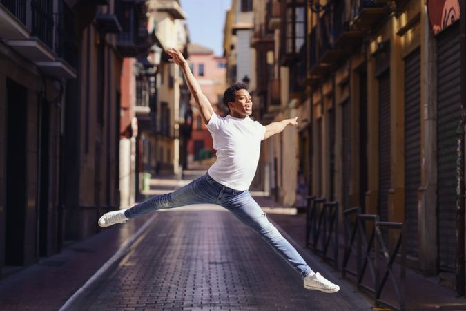 Graceful male dancer leaping on an empty European street