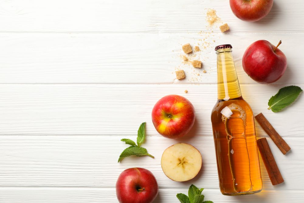 Composition with cider, cinnamon and apples on wooden background