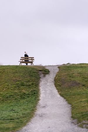 Woman sitting on bench on rainy day
