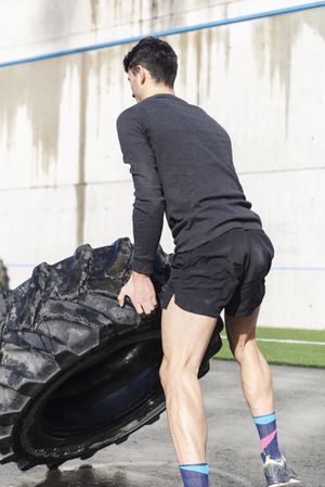 Man training with tire on sports ground