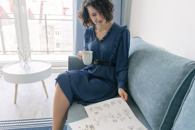 Young brunette woman with coffee looking album with pictures
