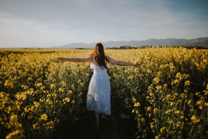 Anonymous woman walking in flower field