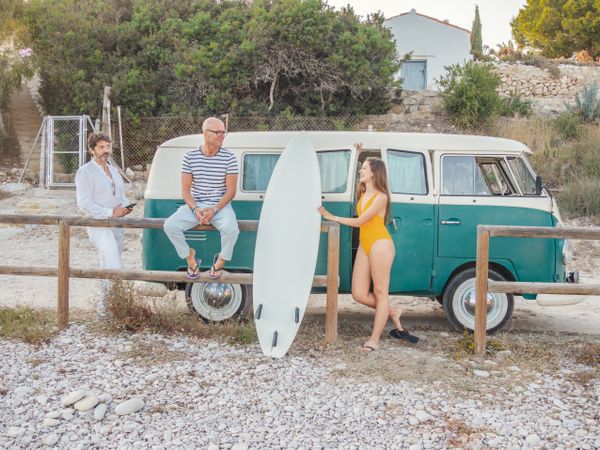 family standing with surfboard near car
