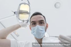 Dentist wearing surgical mask while holding angled mirror, ready to begin exam 5aNxG4