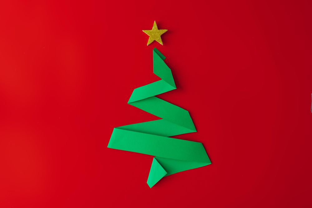 Minimal origami style folded paper Christmas tree on red background