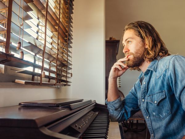 Thoughtful male playing synthesizer at home