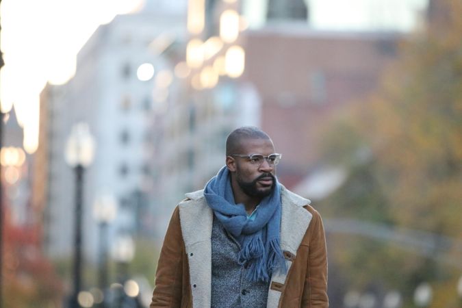 Man with eyeglasses and scarf standing outdoor in city