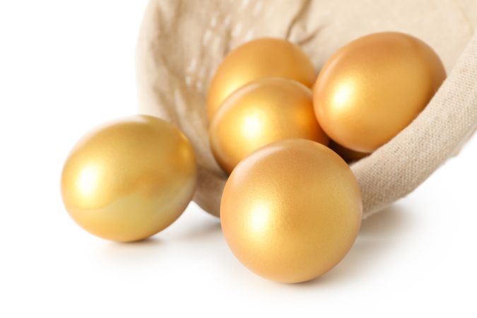 Concept of Richness, golden eggs, isolated on plain background