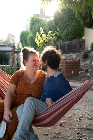 Loving couple about to kiss while sitting in hammock in garden