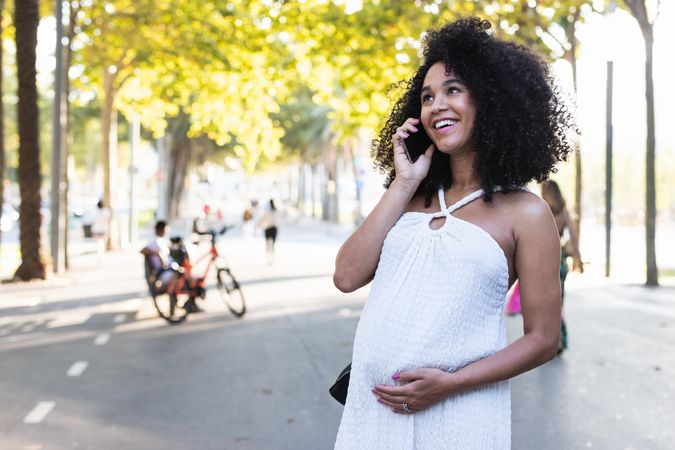 Smiling Black pregnant woman talking on smartphone
