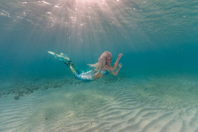 Blond fairytale female mermaid swimming underwater