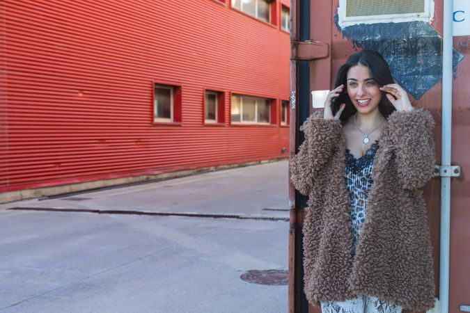 Trendy woman with smartphone near wall