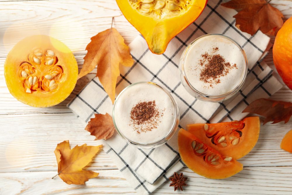 Composition with pumpkin latte on neutral wooden table
