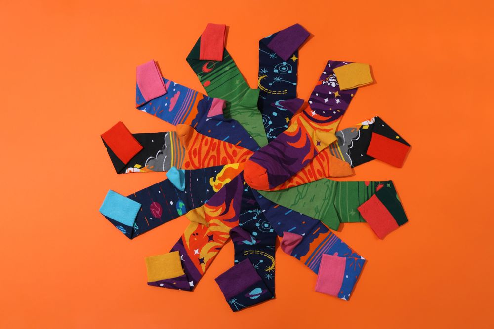 Bright socks with a print, in a pile on an orange background.