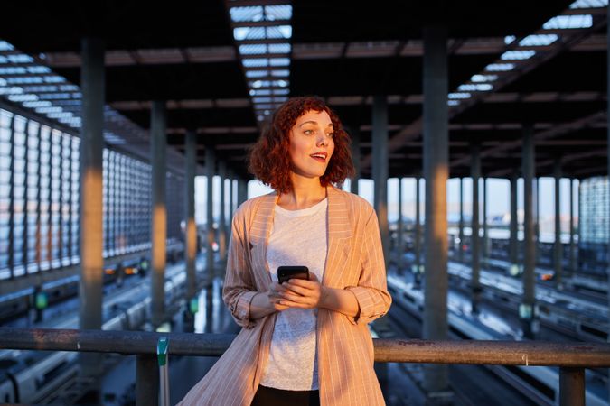 Smiling young woman holding phone at station