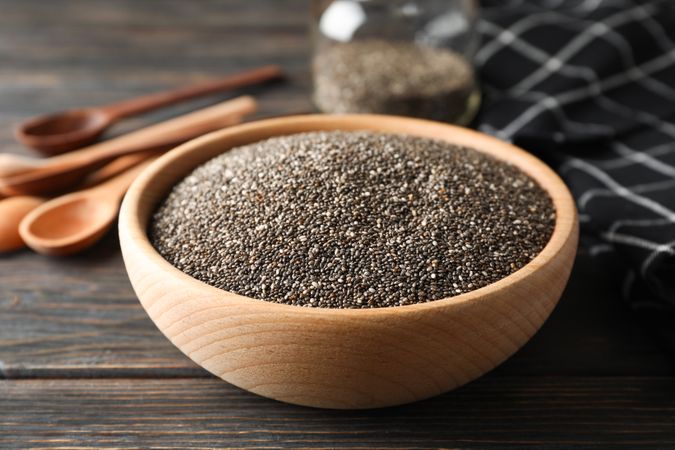 Chia in wooden bowl on wood background, close up