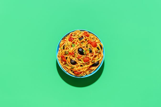 Vegan pasta, spaghetti puttanesca, top view on a green background