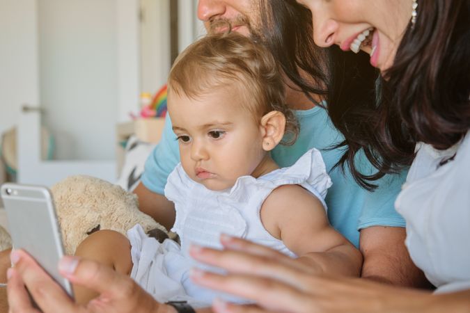 Crop parents with girl using smartphone