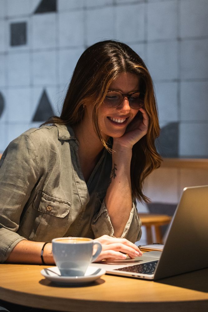 Smiling woman surfing internet on laptop at cafe table