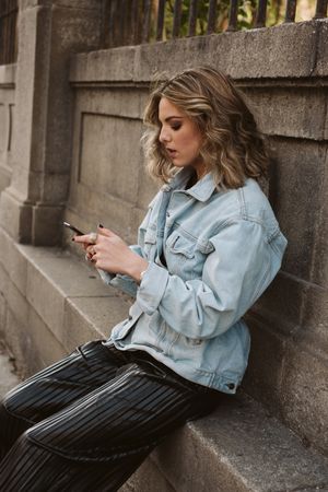 Woman using smartphone near park fence