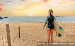 Woman standing on beach with surfboard gazing out at beautiful view 5l2lvb