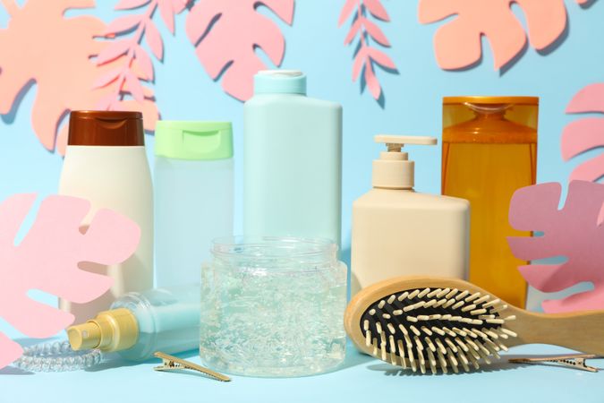 Composition with hairdressing accessories and paper palm leaves on blue background