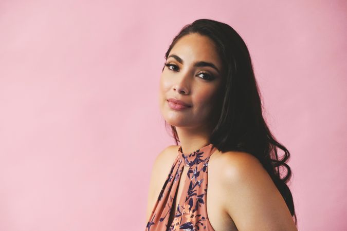 Hispanic woman looking at camera in pink room