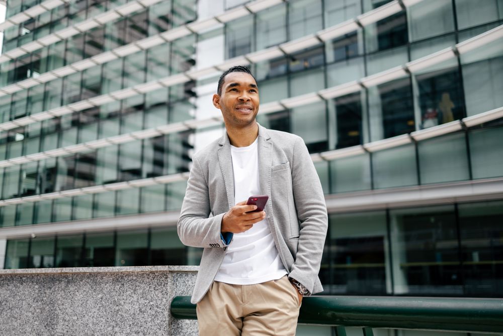 Man using smartphone leaning against wall