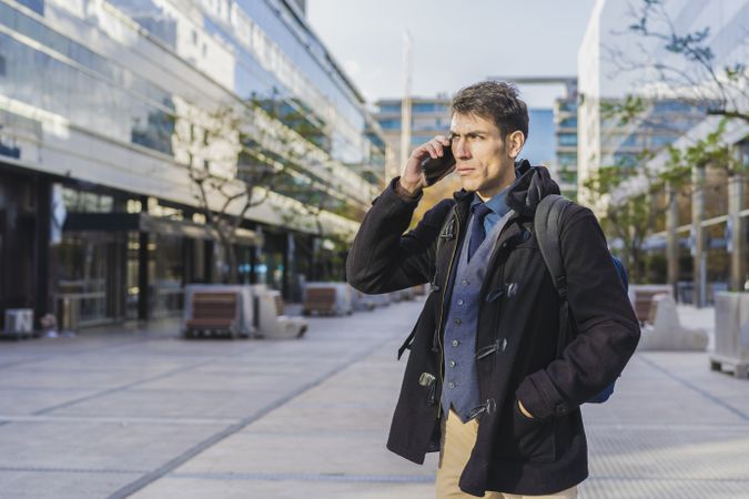 A handsome businessman is talking on the cell phone near his office. Copy space