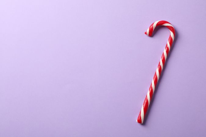 Sweet candy cane on color background, space for text