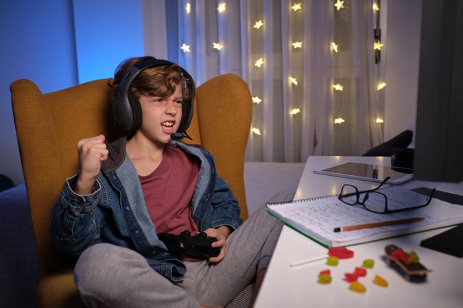 Excited boy playing video game at table