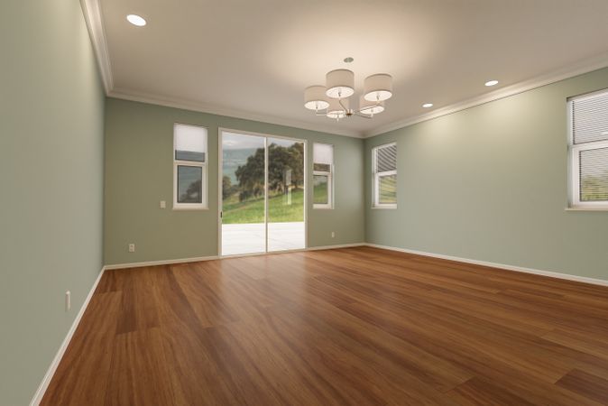 Newly Remodeled Room of House with Finished Wood Floors, Moulding, Light Green Paint and Ceiling Lights.
