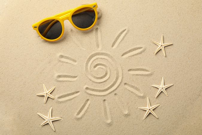 Sun, starfishes and sunglasses on sea sand, top view