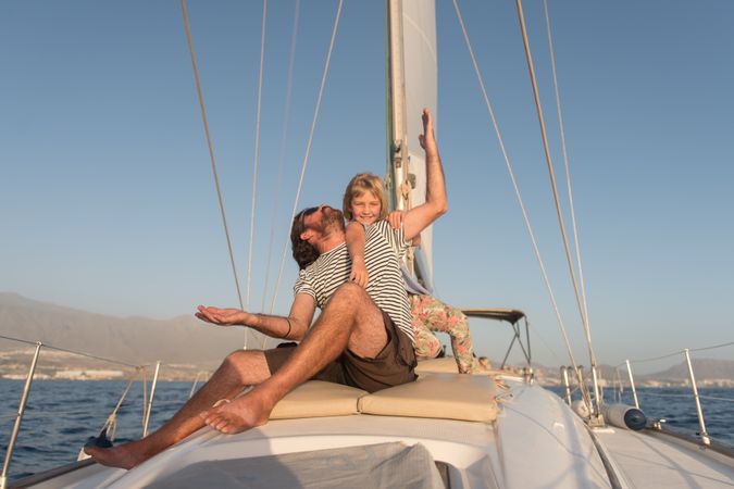 Man having fun with smiling girl and sitting on deck of yacht in sea