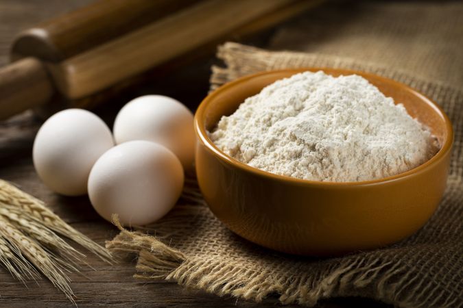 Bowl with wheat flour on the table.