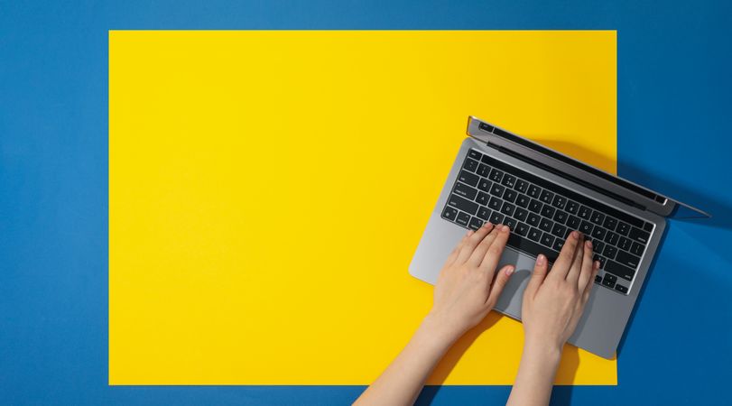 Top view of woman using laptop on yellow blue table