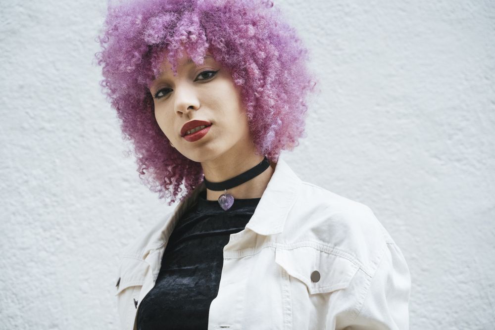 Stylish woman with pink hair looking at camera