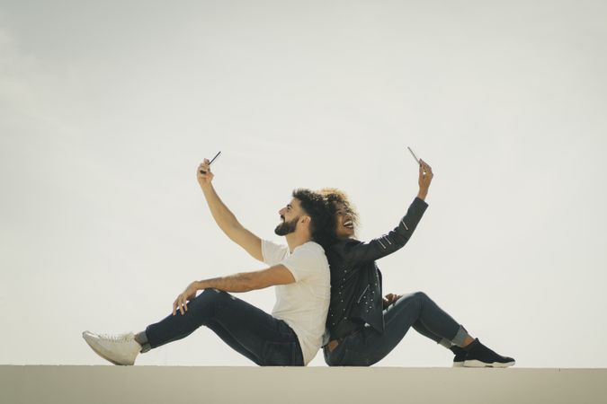 Happy couple taking selfies on wall