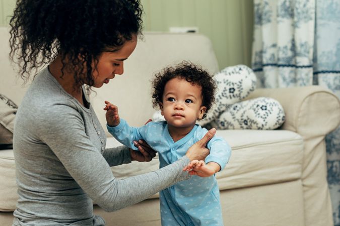 Mother helping toddler son take a few steps