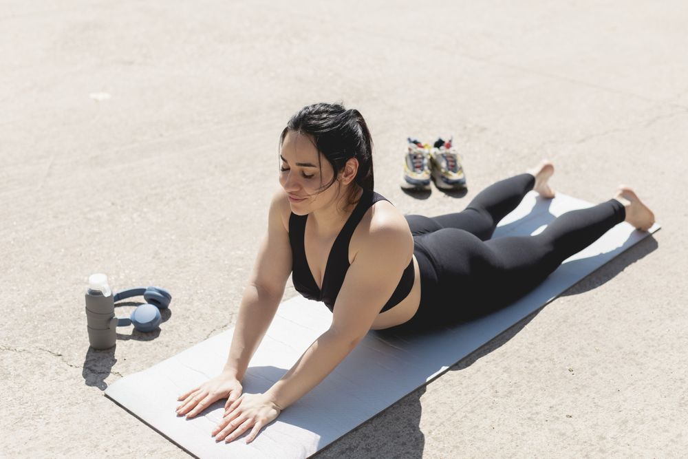 A woman performs exercises and stretches, barefoot, on the mat, after doing sports in the morning