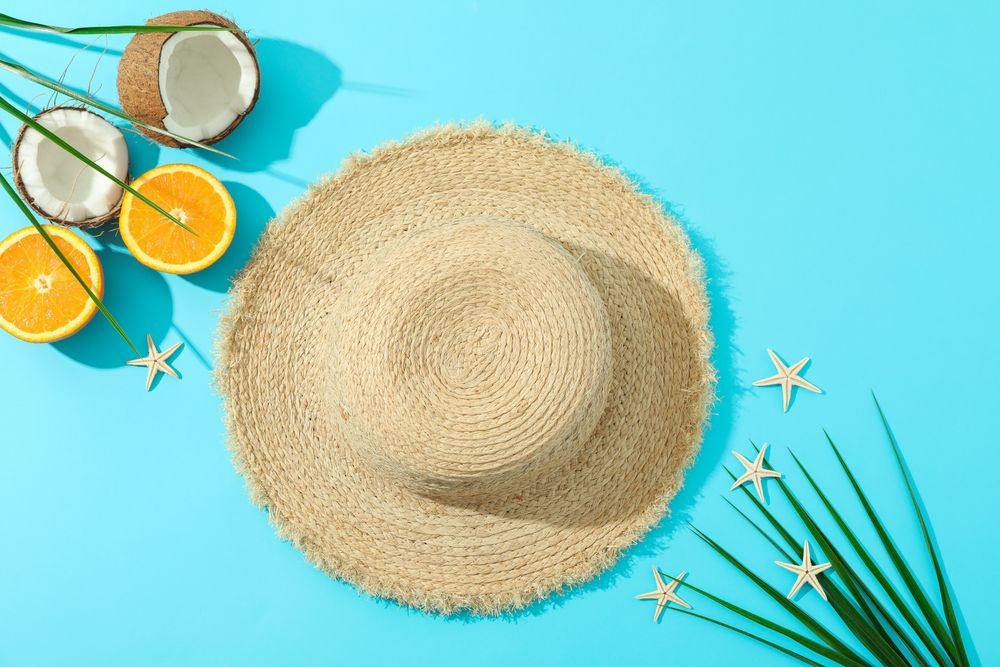 Straw hat, oranges, coconuts, palm leaves and starfishes on color background, space for text and top view. Summer vacation backdrop