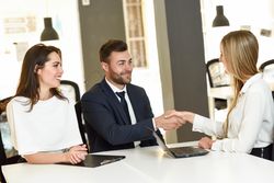 One man with two women ending a meeting together in a stylish office