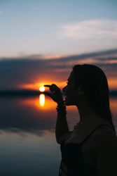 Content woman in swimwear holding sun on beach at sunset