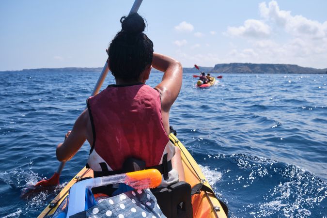 Faceless woman rowing kayak on sea