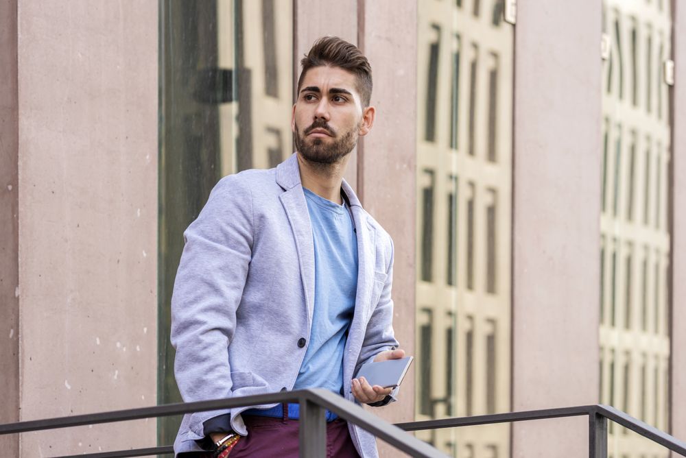 Man holding his mobile phone standing outside building