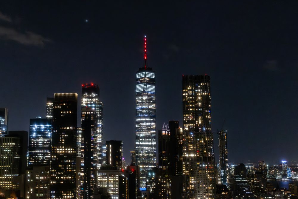 Night Aerial Shot of the One World Trade Center Skyscraper with Antenna. Helicopter Photo of a Group of Glass Buildings in Manhattan