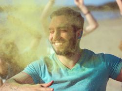 Close-up Portrait of a Muscular Man Dances in Celebration of Holi Festival With His Friends.