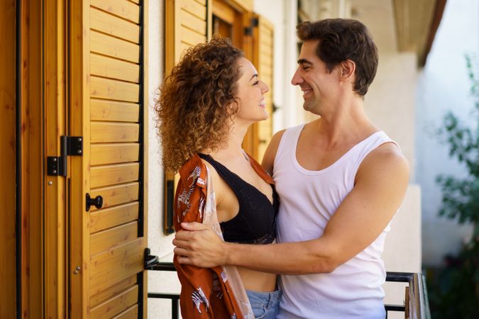 Loving young couple enjoying time while standing on balcony of modern building